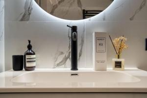 um balcão de casa de banho com um lavatório e um espelho em Canal Couture: Navigli Luxury Retreat em Milão