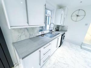 a kitchen with white cabinets and a clock on the wall at Modern Luxury 2 Bed with Parking in Catford