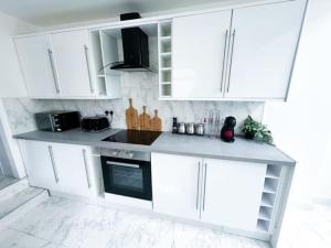 a white kitchen with white cabinets and a stove at Modern Luxury 2 Bed and Private Studio Room with Parking in Catford +16 photos