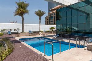 a swimming pool in front of a building with palm trees at Frank Porter - Gold Crest Views in Dubai