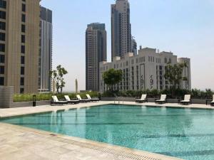 a large swimming pool with lounge chairs and a city at Frank Porter - Creek Horizon T1 in Dubai