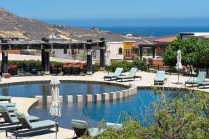 a swimming pool with lounge chairs and the ocean at Spacious New 3BR Villa at Copala-Quivira in Cabo San Lucas