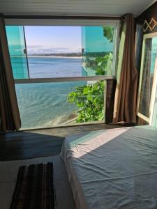 a bedroom with a view of the ocean from a window at Pousada Marambaia Café in Barra de Guaratiba