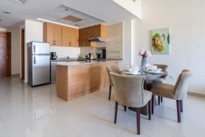 a kitchen with a table with chairs and a refrigerator at Frank Porter - Suburbia in Dubai