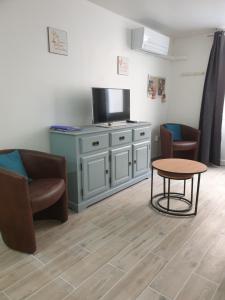 - un salon avec une télévision, une table et des chaises dans l'établissement Saint Laurent de la Salanque Charmant T2 classé 3 étoiles, à Saint-Laurent-de-la-Salanque