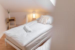 Cama en habitación con sábanas y almohadas blancas en Koje Acht I zentral, mit Sauna, bis zu 9 Personen, en Bremerhaven