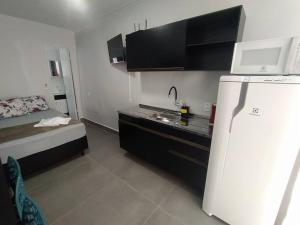 a small kitchen with a refrigerator and a bed at Casa Container Azul Mariscal in Bombinhas