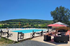 a swimming pool with tables and chairs next to a pool at Glamping Lac du Causse in Lissac-sur-Couze