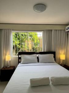 a bedroom with a large white bed with a window at Casa Colibrí. in Manta