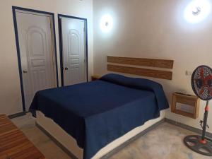a bedroom with a blue bed and a fan at El Bucanero in Las Terrenas