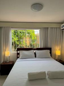 - une chambre avec un grand lit blanc et une fenêtre dans l'établissement Casa Colibrí., à Manta