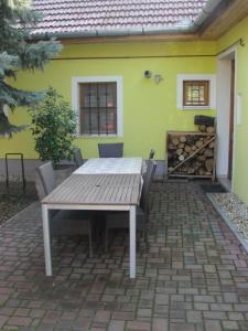 a table and chairs in front of a yellow house at Zanati Apartmannház in Nagykapornak