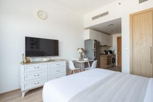 a white bedroom with a white bed and a kitchen at Frank Porter - Azizi Aura in Dubai