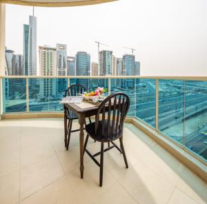 a table and chairs on a balcony with a view of a city at Frank Porter - Yacht Bay in Dubai