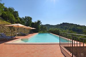 - une piscine avec des chaises et des parasols sur une terrasse dans l'établissement Borgo Gatteraia, à Volterra