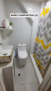 uma casa de banho com um WC branco e um lavatório. em Hogar Marujita em Iquitos