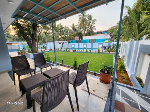 a patio with chairs and a table and a lawn at Basil Leaf Resort in Alibag