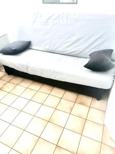 a bed with two pillows sitting on a tiled floor at Appartement charmant à Cabourg avec piscine partagée (24 m²) in Cabourg +6 photos