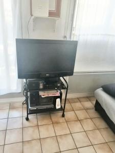 a flat screen tv on a stand in a living room at Appartement charmant à Cabourg avec piscine partagée (24 m²) in Cabourg