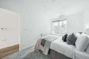 a white bedroom with a bed and a window at Stylish & Spacious 1 Bed Apartment in Barking