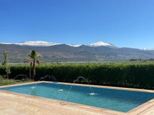 een zwembad met sneeuw bedekte bergen op de achtergrond bij Villa Deluxe Au Pied de l'Atlas in Ksar et Tlatia