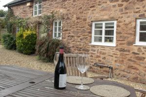 a bottle of wine sitting on a table with a glass at The Barn Timberscombe in Timberscombe
