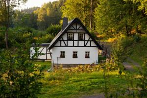 ein weißes Haus mit schwarzem Dach auf einem Feld in der Unterkunft Chalupa Dlouhý Důl 19 in Krásná Lípa