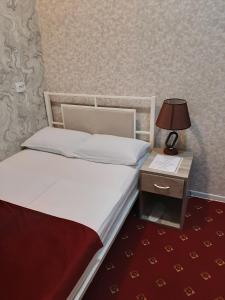 a bedroom with a bed and a night stand with a lamp at Hotel Erebuni Plaza in Yerevan