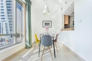 a dining room with a table and chairs and a large window at Frank Porter - Blakely Tower in Dubai