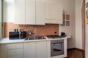 cocina con armarios blancos, fregadero y microondas en A due passi da Santa Maria Maggiore Apartment, en Roma