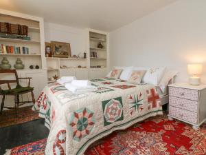 een slaapkamer met een bed met een quilt bij Blackbird Cottage in Bideford