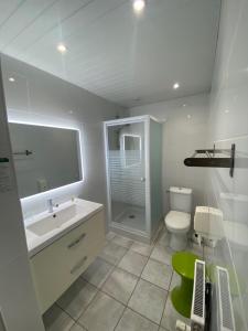 a white bathroom with a sink and a toilet at Hotel Le Pelican in Charleville-Mézières