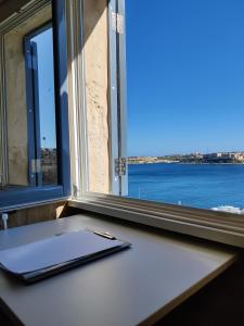 un cuaderno sentado en un escritorio junto a una ventana en Cove 532 by Savynomad Harbour Residences wow View, en La Valeta