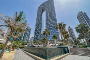 a tall building with palm trees in front of it at Frank Porter - The Address JBR in Dubai