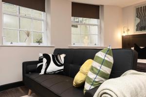 ein schwarzes Sofa im Wohnzimmer mit Fenstern in der Unterkunft Charming Brighton Studio Flat in Brighton & Hove