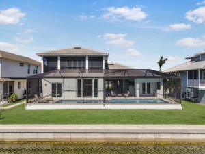a large white house with a pool in the yard at 2024 Monsterrat model waterfront home with lap pool in Marco Island