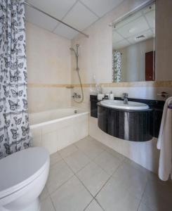 a bathroom with a toilet and a tub and a sink at Frank Porter - Elite Residence in Dubai