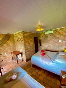a bedroom with two beds and a brick wall at Pousada Da Bell in Barreirinhas