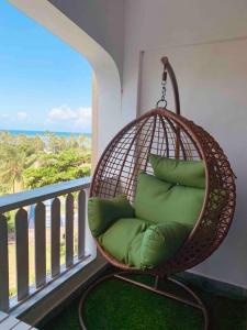 a hanging rattan chair with pillows on a balcony at Bahari Studio Beach Front Apartment. in Diani Beach +22 photos