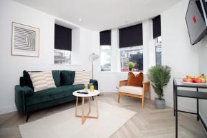 - un salon avec un canapé vert et une table dans l'établissement Centrally Located 2 Bedroom, à Cardiff