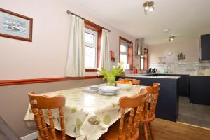 BlairmoreにあるBirch Cottageのテーブル、椅子、テーブル、キッチン付きのキッチンが備わります。