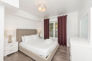 a white bedroom with a bed and a window at Courtyard Apartments Part of the Oasis Casita Collection in Miami Beach