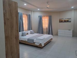 a bedroom with a large bed with blue curtains at Deluxe Résidence Ouaga 2000 in Ouagadougou