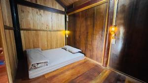 Habitación pequeña de madera con cama. en Homestay Yến Long, en Hữu Lũng