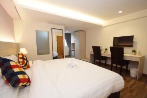 a hotel room with a white bed and a desk at Good Luck Inn in Ayer Itam