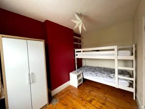 sypialnia z białym łóżkiem piętrowym i czerwoną ścianą w obiekcie The Claude House w mieście Bath