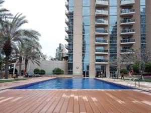 a swimming pool in front of a tall building at Frank Porter - Marina Tower in Dubai