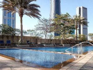 a swimming pool with palm trees and buildings at Frank Porter - The Lofts in Dubai