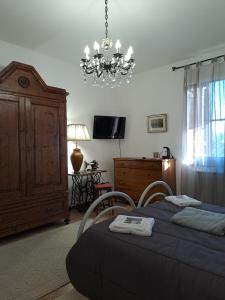 1 dormitorio con 1 cama con 2 sillas y una lámpara de araña en Casale Crisanti en Beroide