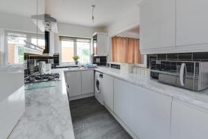 uma grande cozinha com bancadas brancas e electrodomésticos em Remarkable 3-Bed House in Middleton Manchester em Manchester